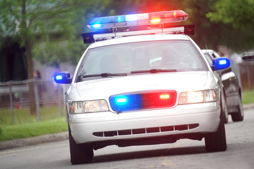 police car driving down the street with lights flashing | criminal defense attorneys
